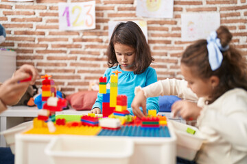 Two kids playing with construction blocks sitting on table at kindergarten