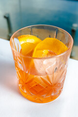 Classic italian negroni cocktail decorated with orange slices on a with the sea background