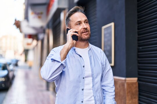 Young caucasian man talking on the smartphone with serious expression at street