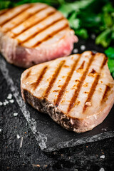 Grilled tuna on a stone board with parsley and salt. 