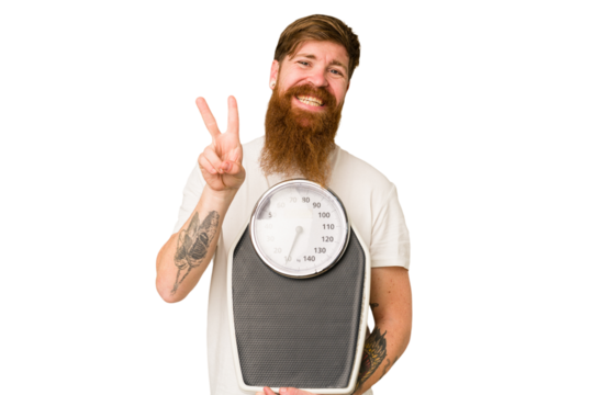 Adult redhead man with long beard holding a scale isolated cut out joyful and carefree showing a peace symbol with fingers.