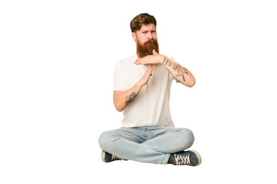 Young adult redhead with a long beard sitting on the floor isolated showing a timeout gesture.