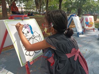 an asian kids with glasses and mask paint and draw at public park, outdoor activity at park