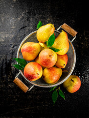 Juicy pears in a colander with foliage.