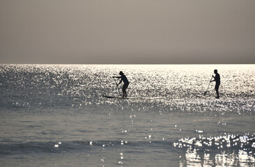 Fototapeta na wymiar Early morning paddle boarding in the ocean at sunrise