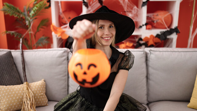 Young blonde woman having halloween party holding pumpkin basket at home