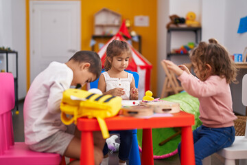 Obraz premium Group of kids preschool students sitting on table drawing on paper at kindergarten