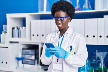 Young african american woman scientist using smartphone at laboratory