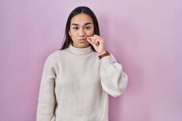 Young south asian woman standing over pink background mouth and lips shut as zip with fingers. secret and silent, taboo talking