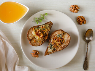 Homemade baked pears with blue cheese, nuts and honey on a plate. French cuisine. Keto diet. Vegetarian lunch. Top view