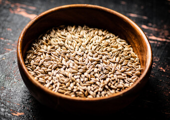 Grain in a wooden bowl on the table. 