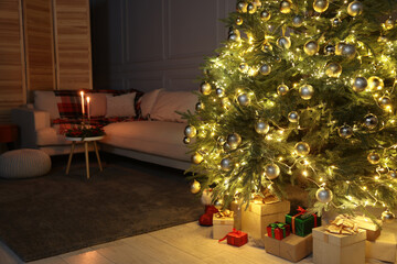 Beautiful glowing Christmas tree, gift boxes and sofa in living room