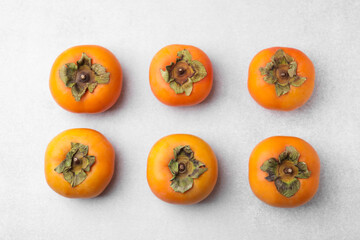 Delicious ripe juicy persimmons on light table, flat lay