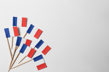 Small paper flags of France on light background, flat lay. Space for text