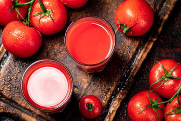 Tomato juice in glasses on a wooden cutting board. 
