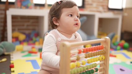 Adorable toddler playing with abacus sitting on floor at kindergarten - Powered by Adobe