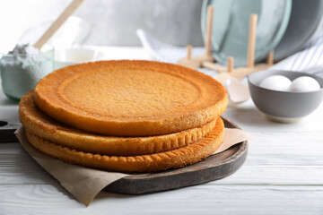 Delicious homemade sponge cakes and ingredients on white wooden table