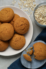 Delicious oatmeal cookies and flakes on light grey table, flat lay