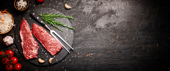 Raw steak on a stone board. On a black background.