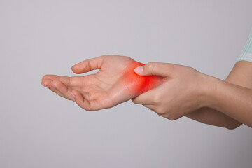Arthritis symptoms. Young woman suffering from pain in wrist on light grey background, closeup - obrazy, fototapety, plakaty