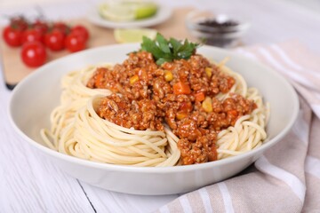 Tasty dish with fried minced meat, spaghetti, carrot and corn on white wooden table, closeup