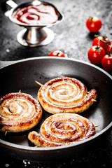 Delicious grilled sausages in a frying pan with fresh tomatoes. 