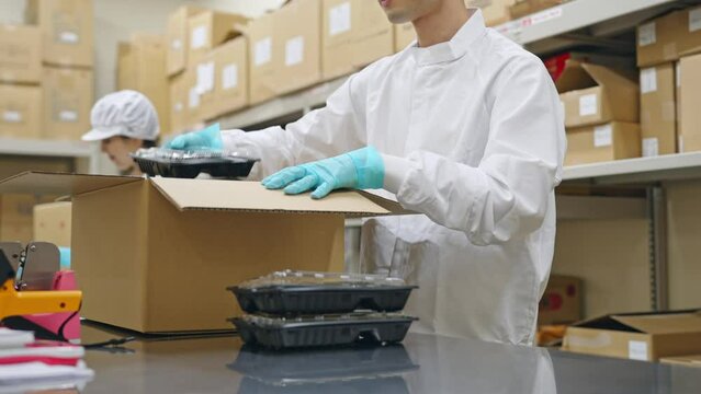 食品を箱詰めする女性　給食センター　宅配食　包装工場