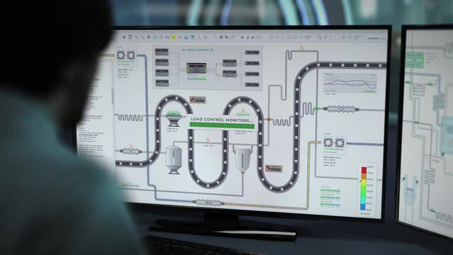 Technician looking at the display for inspection of a production process. Technician monitoring the manufacturing process on a computer display. Technician observing the automation process on display.