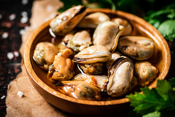 A plate of pickled mussels on paper with parsley. 