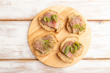 Bread sandwiches with jerky salted meat, sorrel and cilantro microgreen on white. top view.
