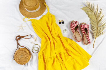 Straw hat and yellow summer dress on the white background. Spring, summer collection of women's clothing, accessories. Casual outfit	