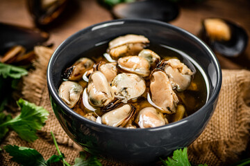 Pickled mussels in a bowl with parsley on burlap. 
