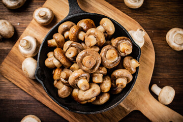 Fried mushrooms in a frying pan on a cutting board. 