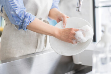 キッチンで環境と肌に優しい食器用洗剤で素手で食器を洗う人