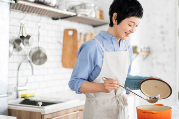 愛情込めて料理をしている女性、鍋の蓋を開けて様子を見ている