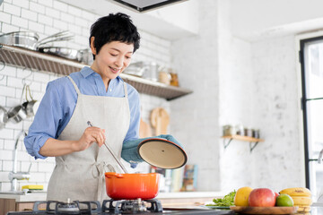 愛情込めて料理をしている女性、鍋の蓋を開けて様子を見ている