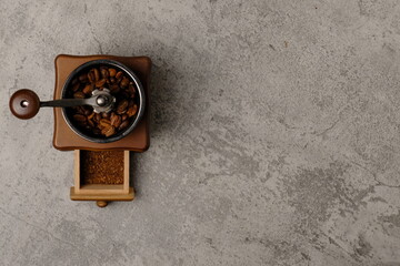 High angle composition of  coffee beans and vintage coffee grinder on abstract background, space for text