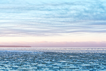 Obraz premium Panoramic view of the shore of the Baltic sea at sunset in winter. Ice fragments in sea close-up. Colorful seacape, soft sunlight. winter sea. The coast of the Gulf of Finland in winter