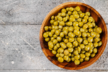 Full wooden plate with canned green peas.