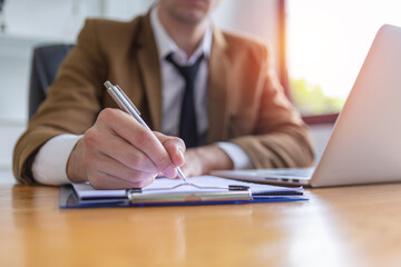 Close up a pen, businessman writing information note on paperwork at office table. manager write down business reports.