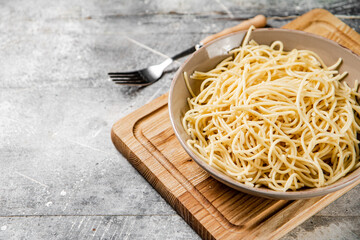 Full bowl with boiled spaghetti on a cutting board. 