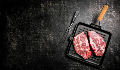 Raw pork steak in a frying pan. 