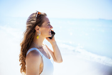 happy stylish woman at beach talking on smartphone