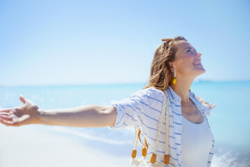 Fototapeta na wymiar smiling stylish 40 years old woman at beach rejoicing