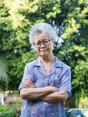 Portrait of a senior woman with short gray hair looking at the camera, staying in her garden