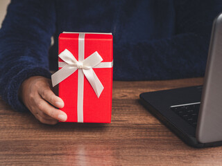 Close-up of hand holding a red gift box while sitting at the table in the office
