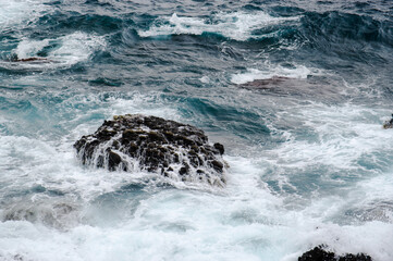 海面に出ている岩に波が押し寄せてくる様子