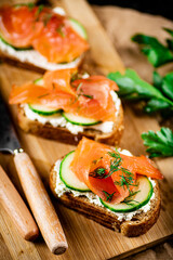 Salmon sandwich on a wooden cutting board. 