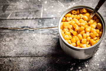 An open can of canned corn with a spoon. 