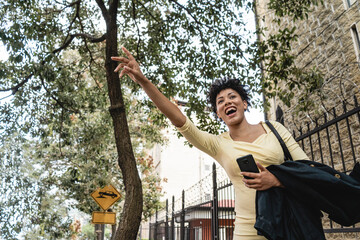 image of a curly-haired latina woman raising her hand and screaming with a cell phone in her hand